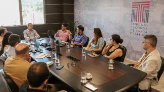 Foto de onze pessoas sentadas diante de uma mesa, enquanto conversam, durante reunião do grupo de trabalho do Programa TCE Educação. Entre elas, o conselheiro substituto Gerson dos Santos Sicca.